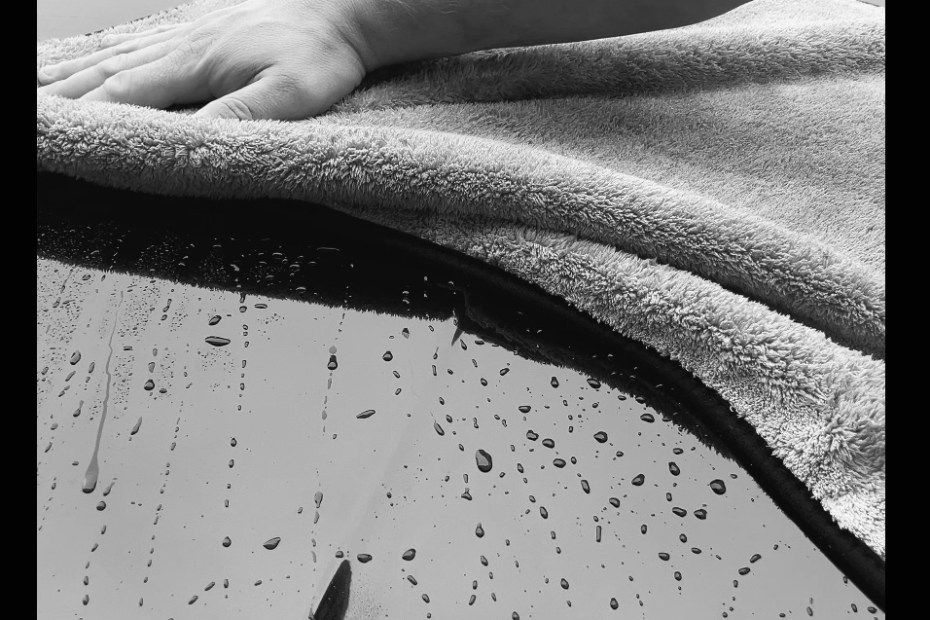 hand wiping car bodywork with towelling cloth